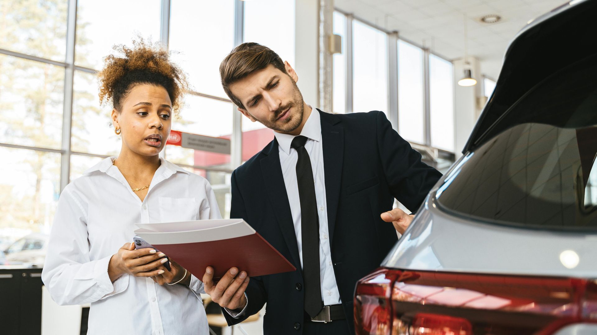 A professional consultation at a car dealership involving a sales agent and a customer discussing a vehicle purchase.