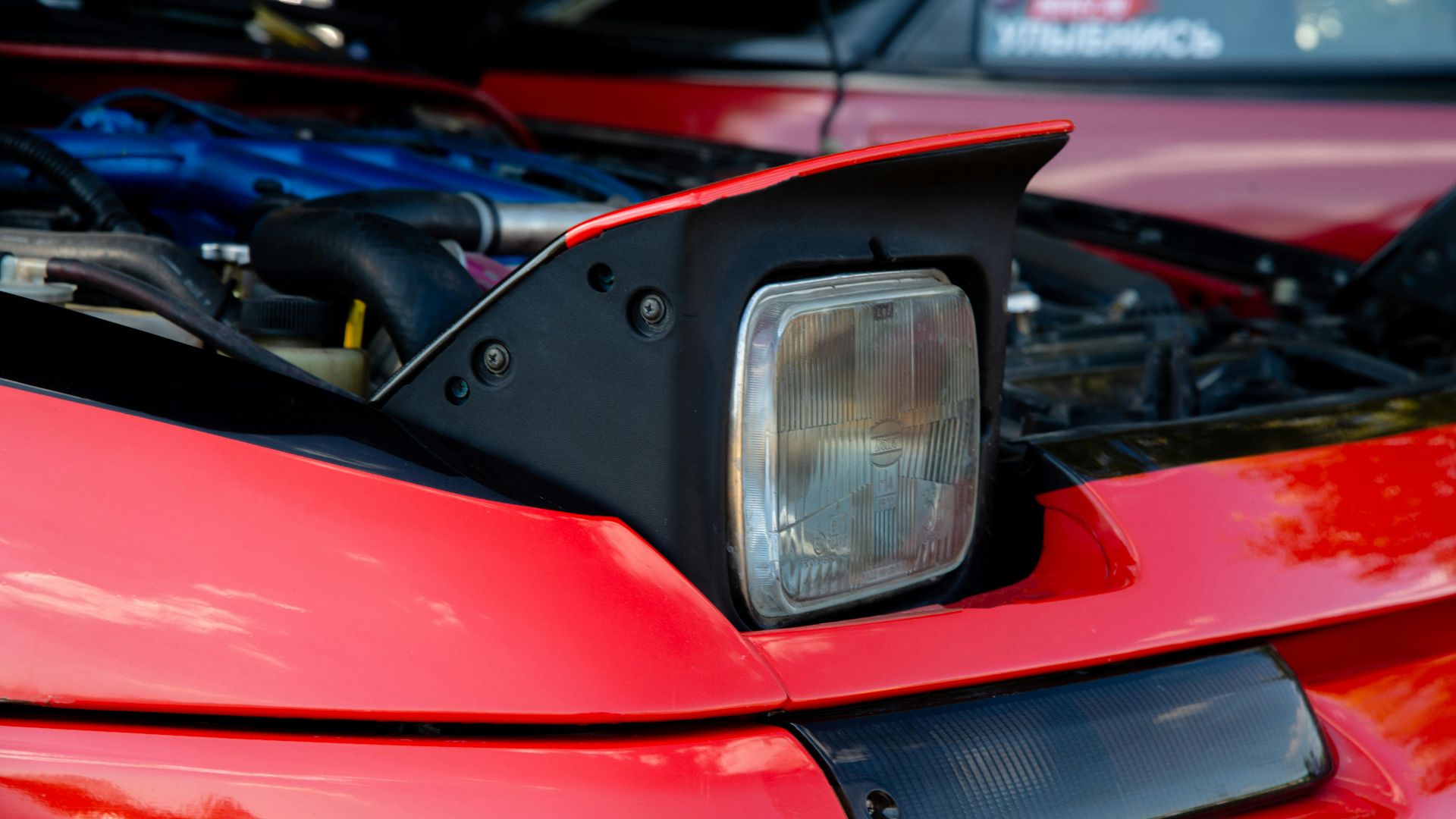 Detailed view of a red sports car with visible engine and pop-up headlight.