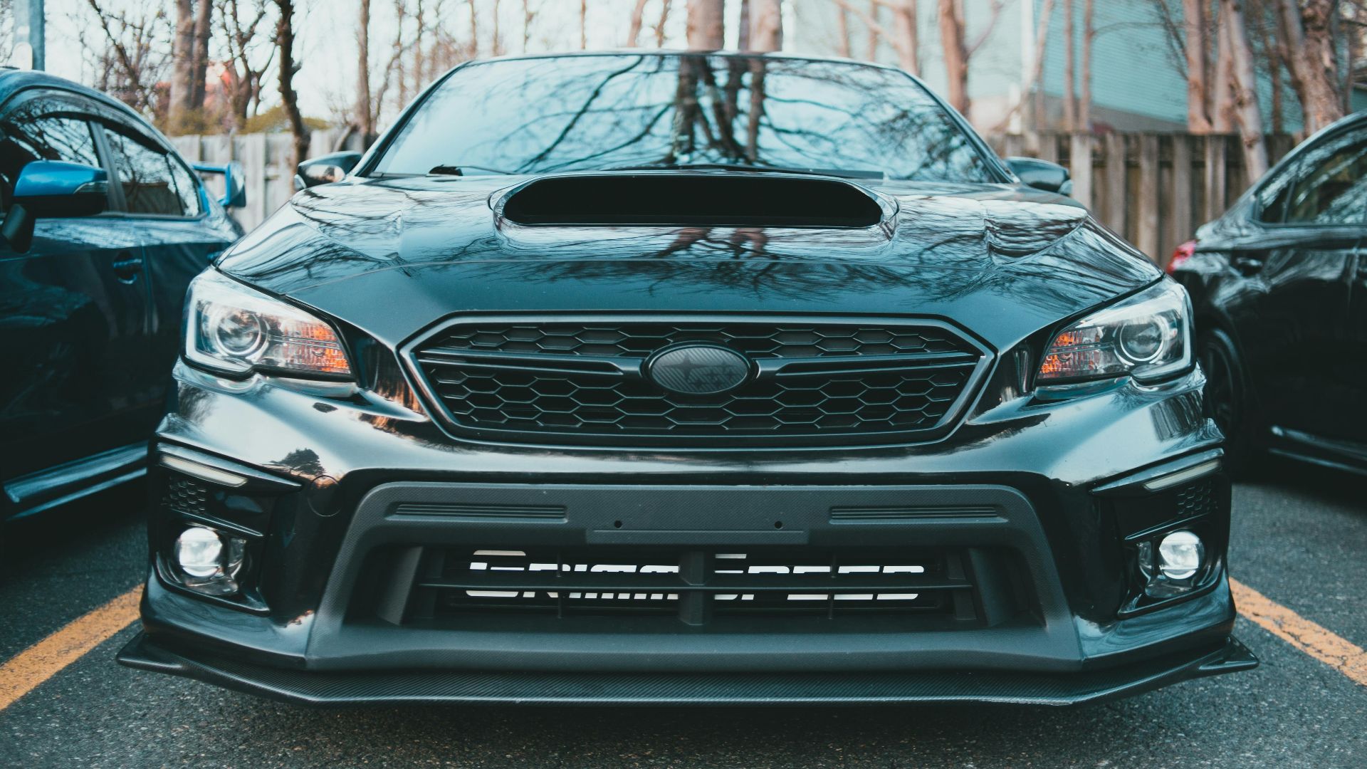 A sleek black Subaru Impreza with a prominent hood scoop, captured in an outdoor setting.