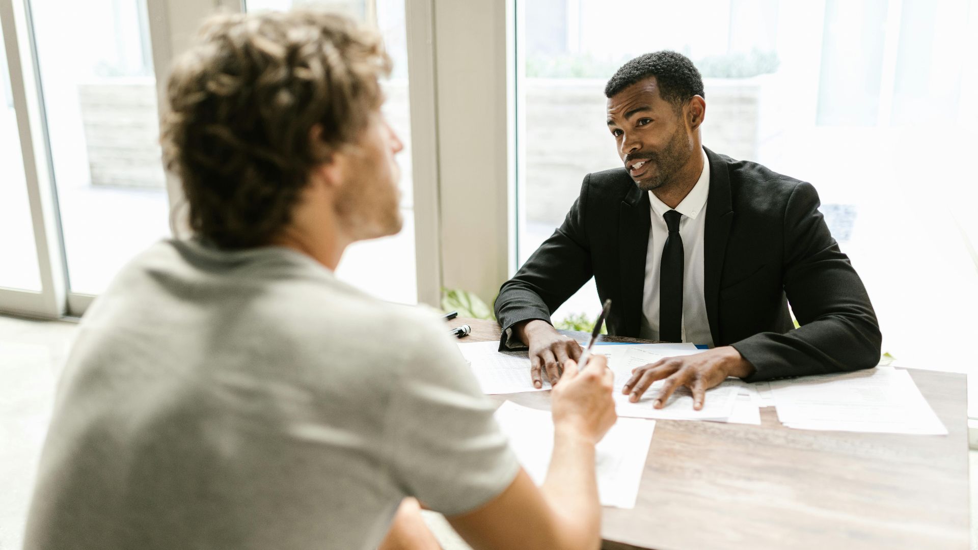 Two men having a discussion over documents in a modern office setting.