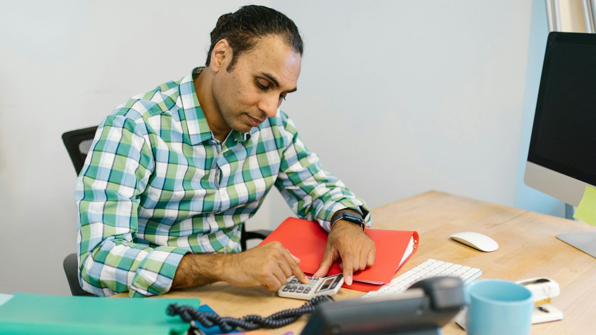 Man engaged in focused calculation work in an office environment.