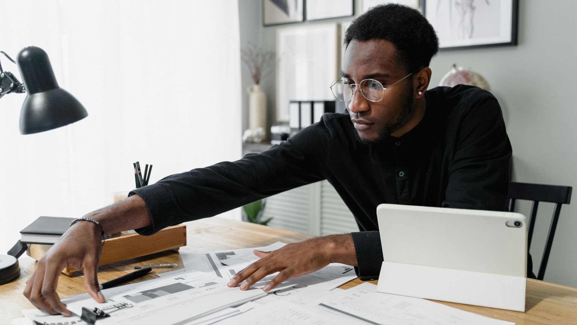Business professional working at desk reviewing financial documents with digital tablet.