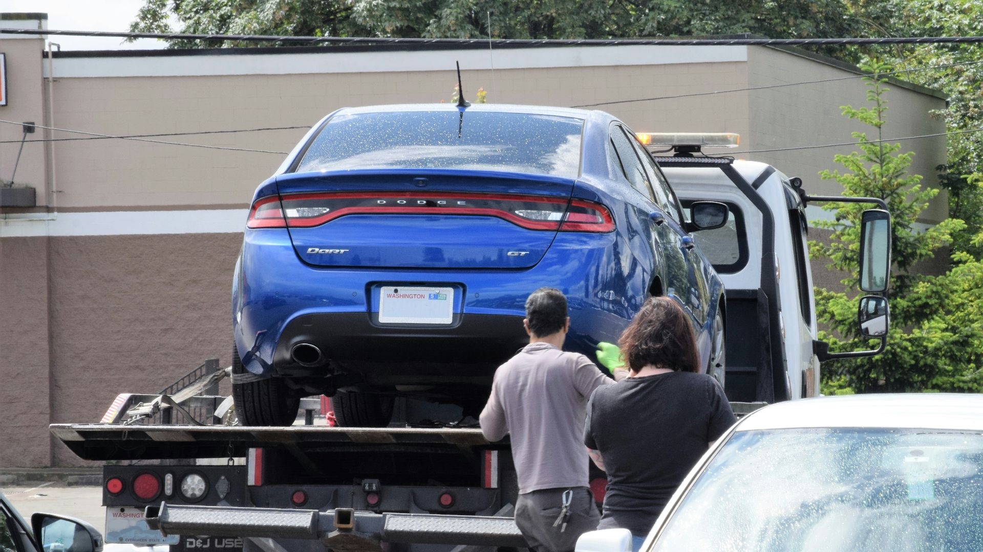 a blue car being loaded onto a flatbed truck