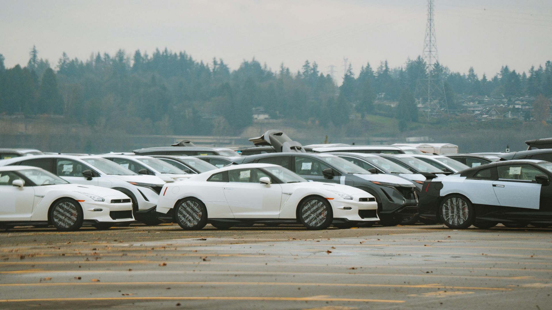 Wide shot of multiple sports cars parked outdoors on a cloudy day.