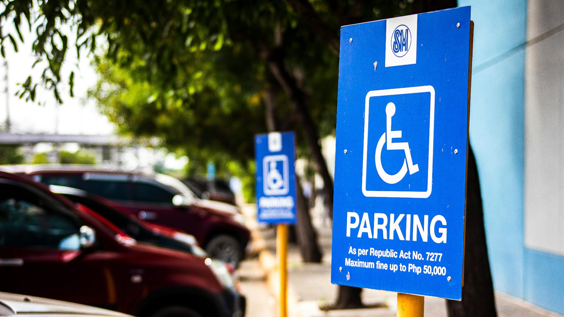 Signboard representing rule for disabled people parking only near vehicles and sidewalk in city