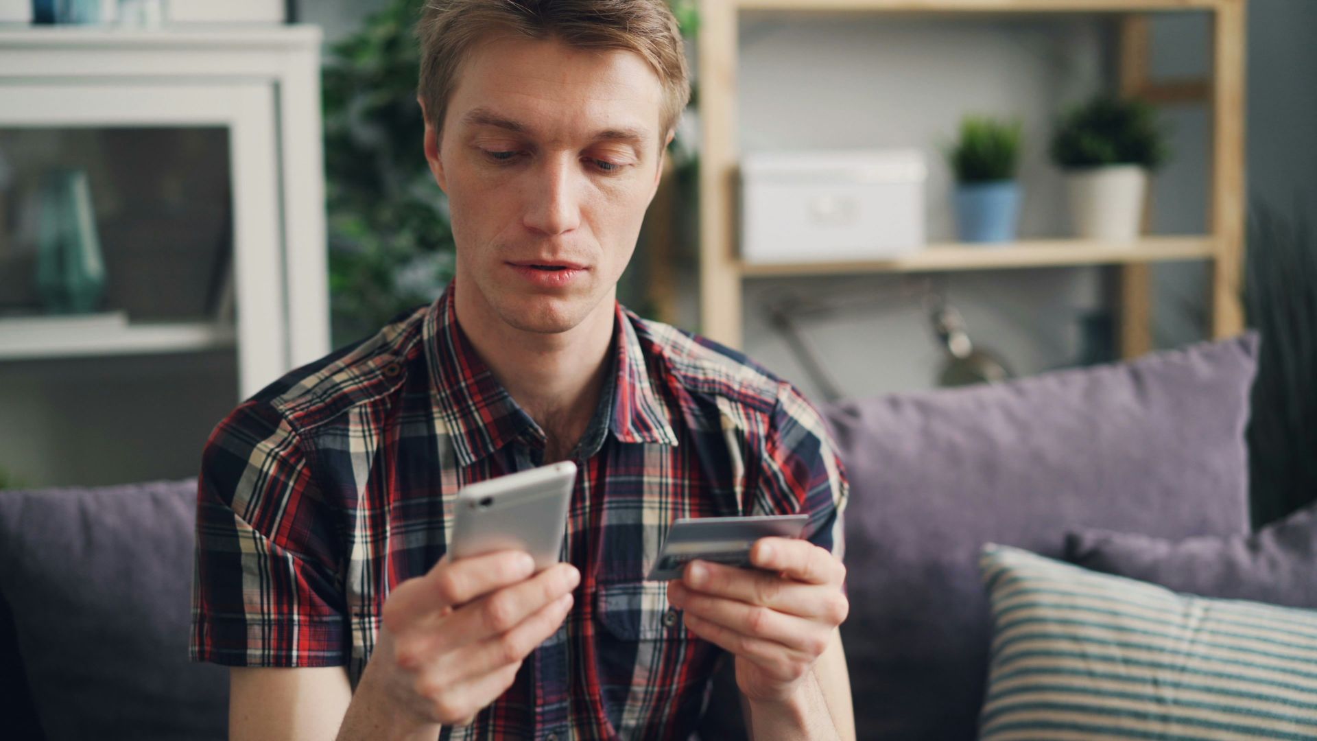 a man sitting on a couch looking at his cell phone
