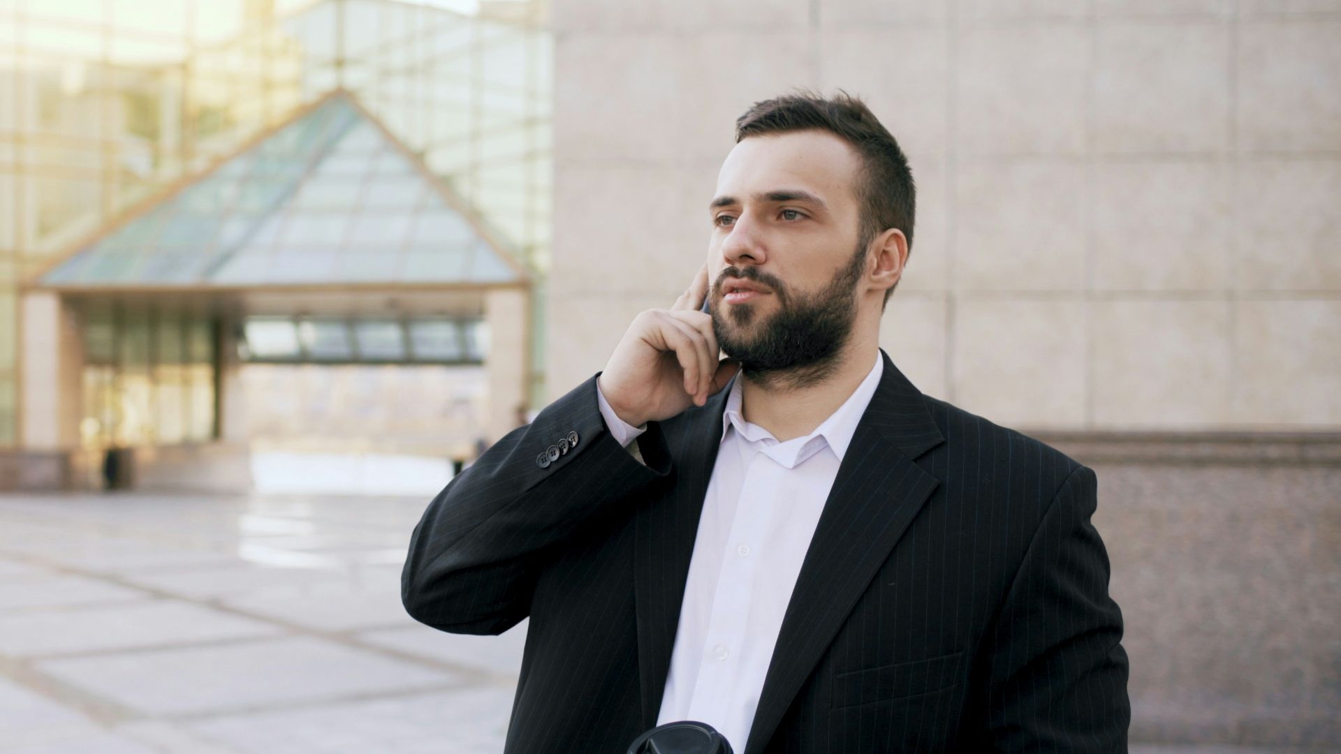 Man in suit talking on phone holding coffee cup