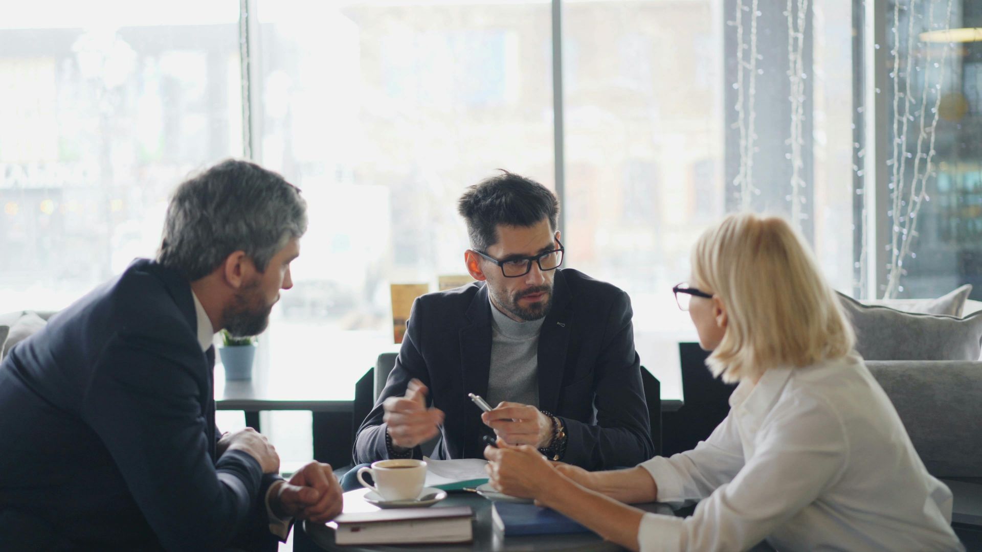 Business professionals engaged in a meeting at a café, sharing ideas and discussion.