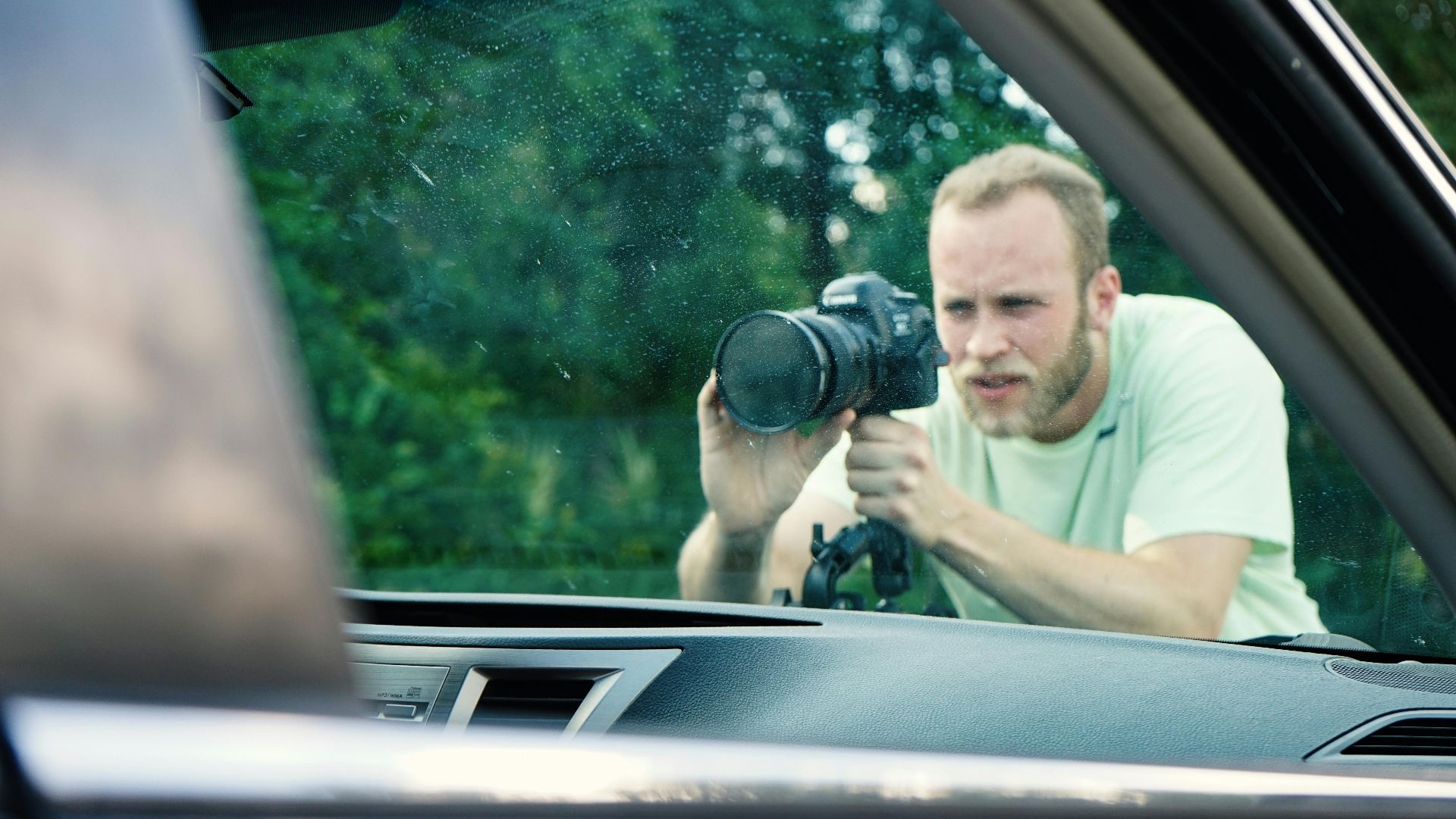 Photographer focusing on details through a car window on a sunny day.
