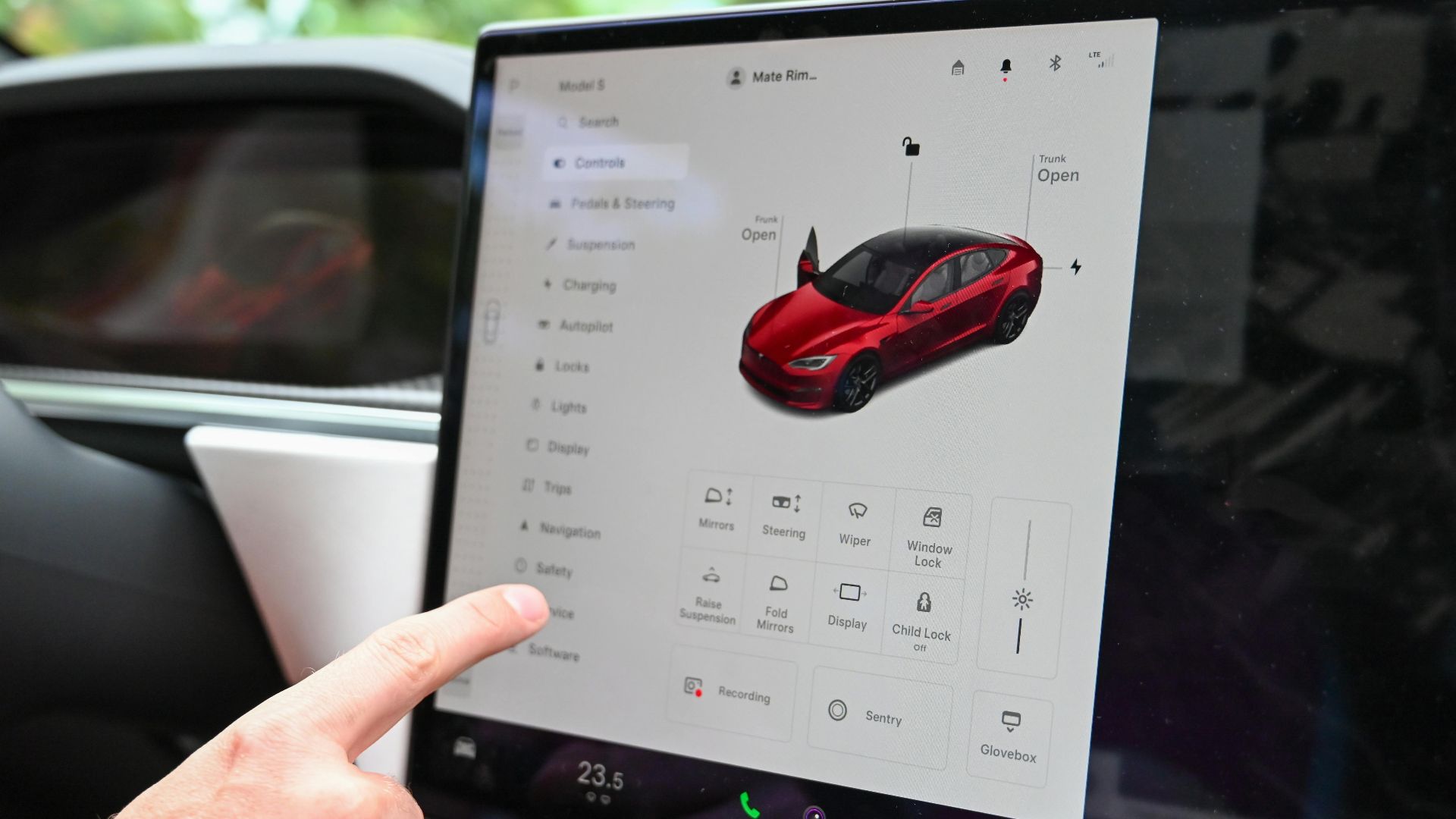 Close-up of a hand interacting with a modern car's touchscreen interface for various controls.