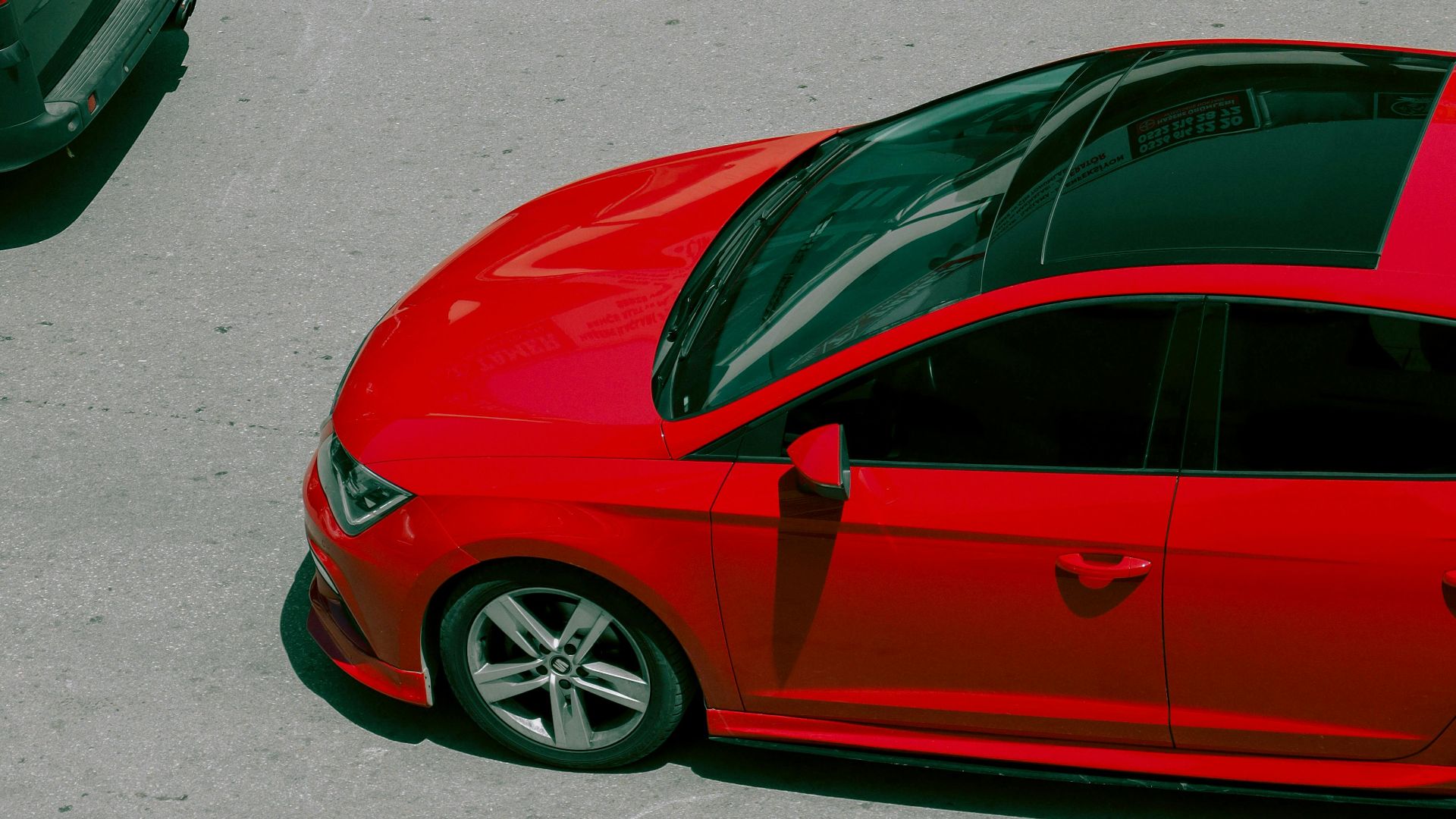 A vibrant red car captured from above on a city street, showcasing modern urban life.