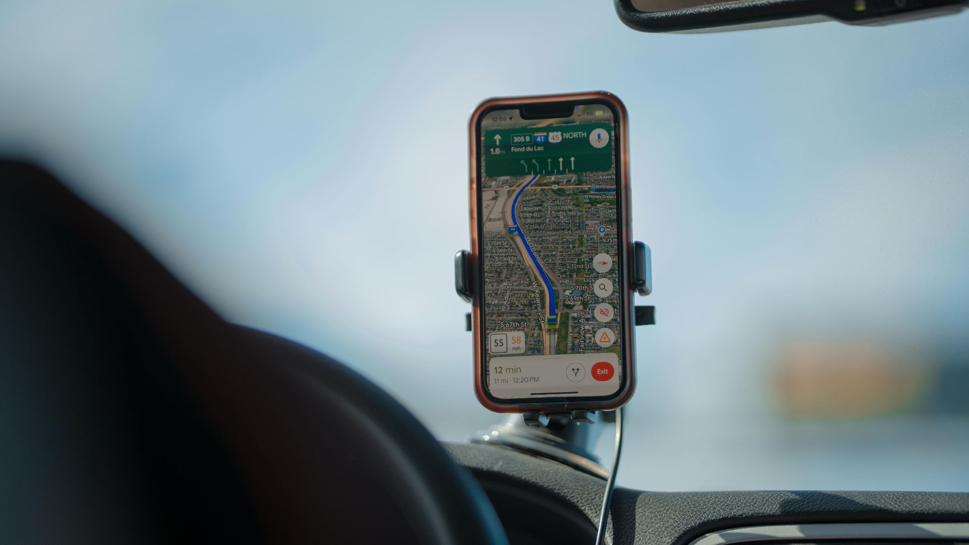A smartphone with GPS navigation app mounted on a car dashboard during a road trip.