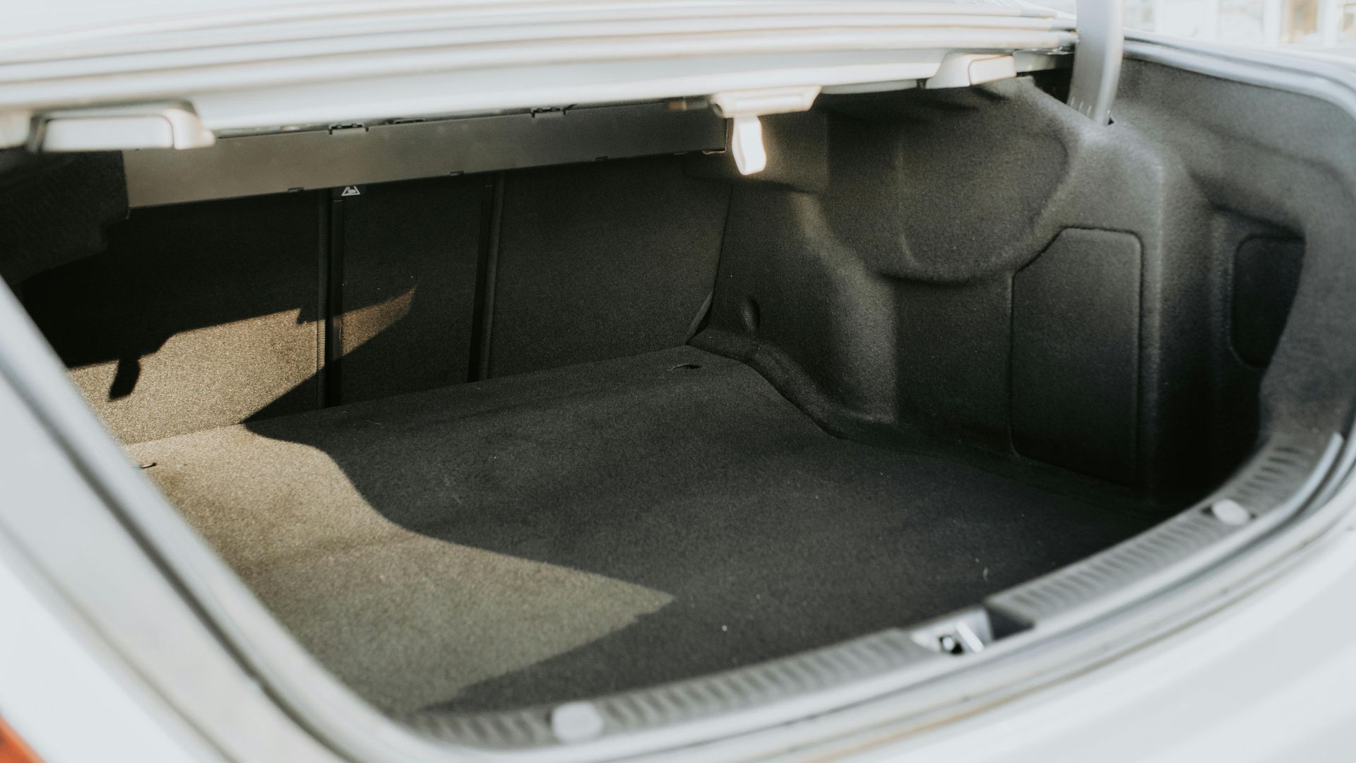 An empty car trunk highlighted by bright sunlight, showing ample space.