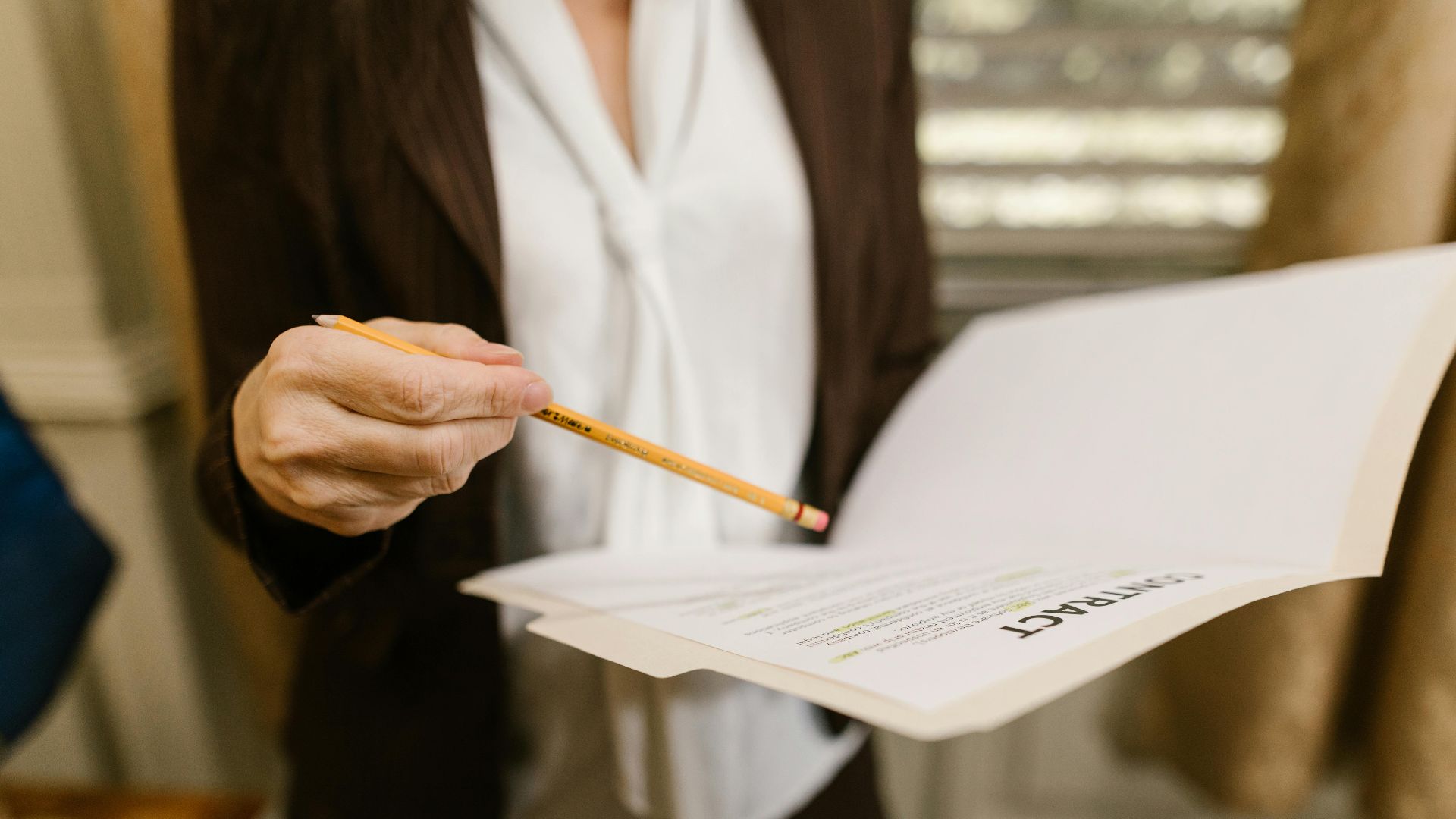 A businesswoman holds a contract, pointing with a pencil. Legal and corporate setting.