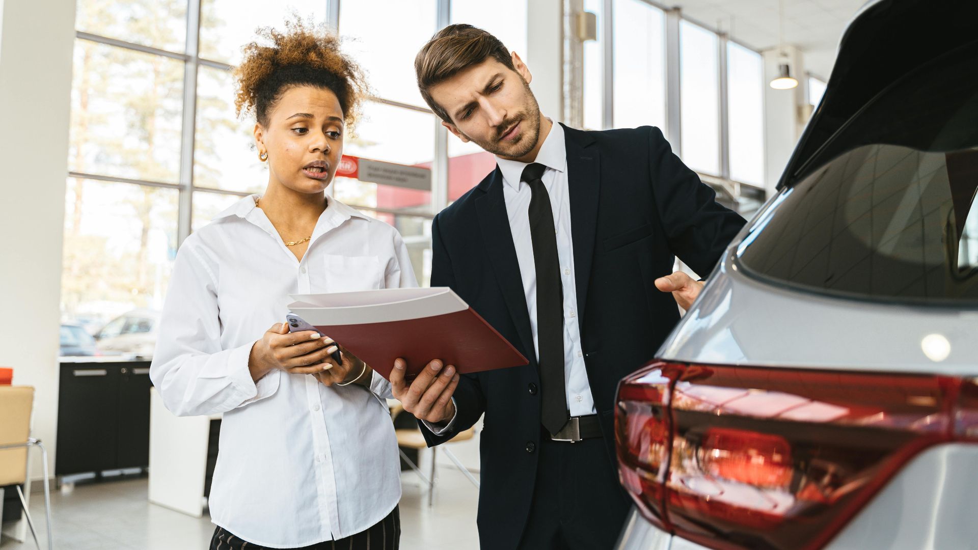 A professional consultation at a car dealership involving a sales agent and a customer discussing a vehicle purchase.