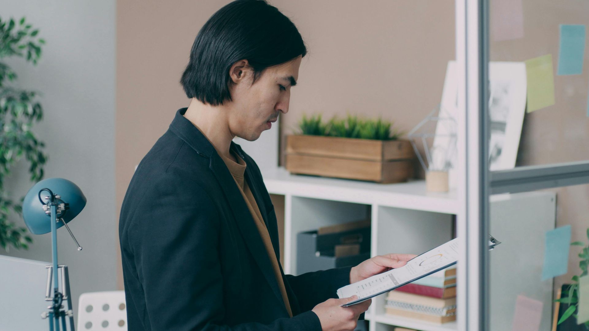 Young man analyzing paperwork in modern office setting.