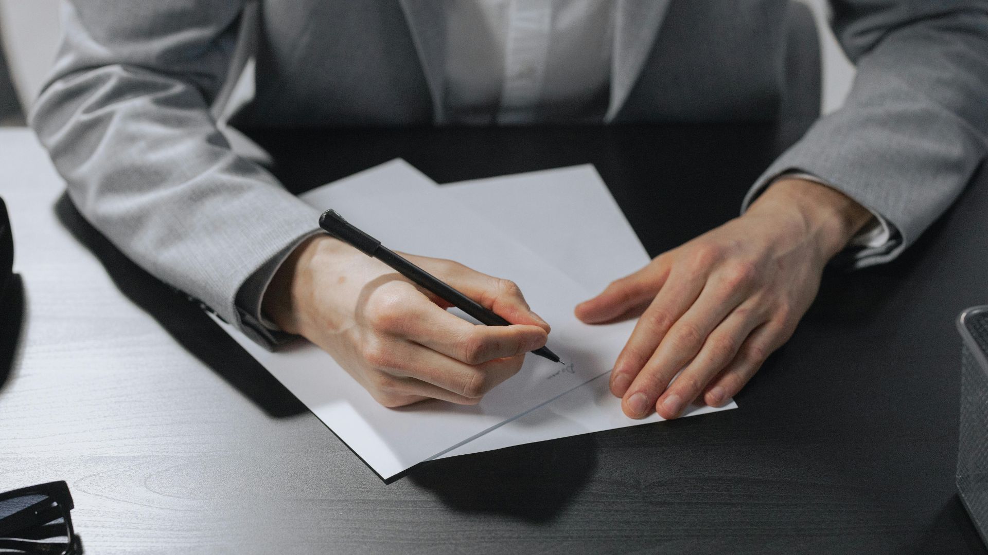 Professional hands signing a document in an office setting for business purposes.
