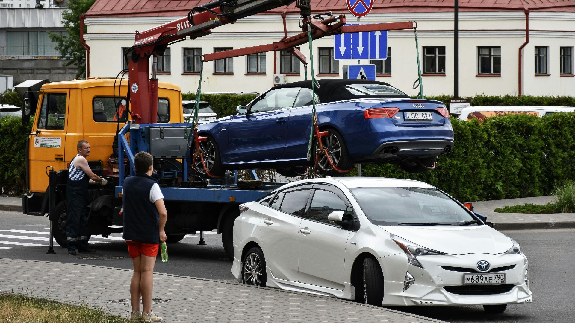 Towing a blue Audi convertible in a bustling city street.