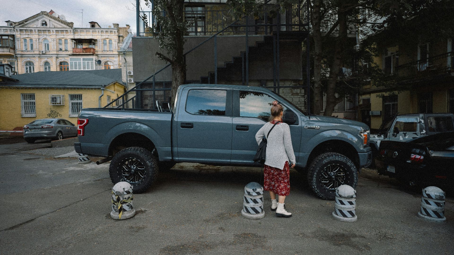 man in white shirt standing beside gray crew cab pickup truck during daytime