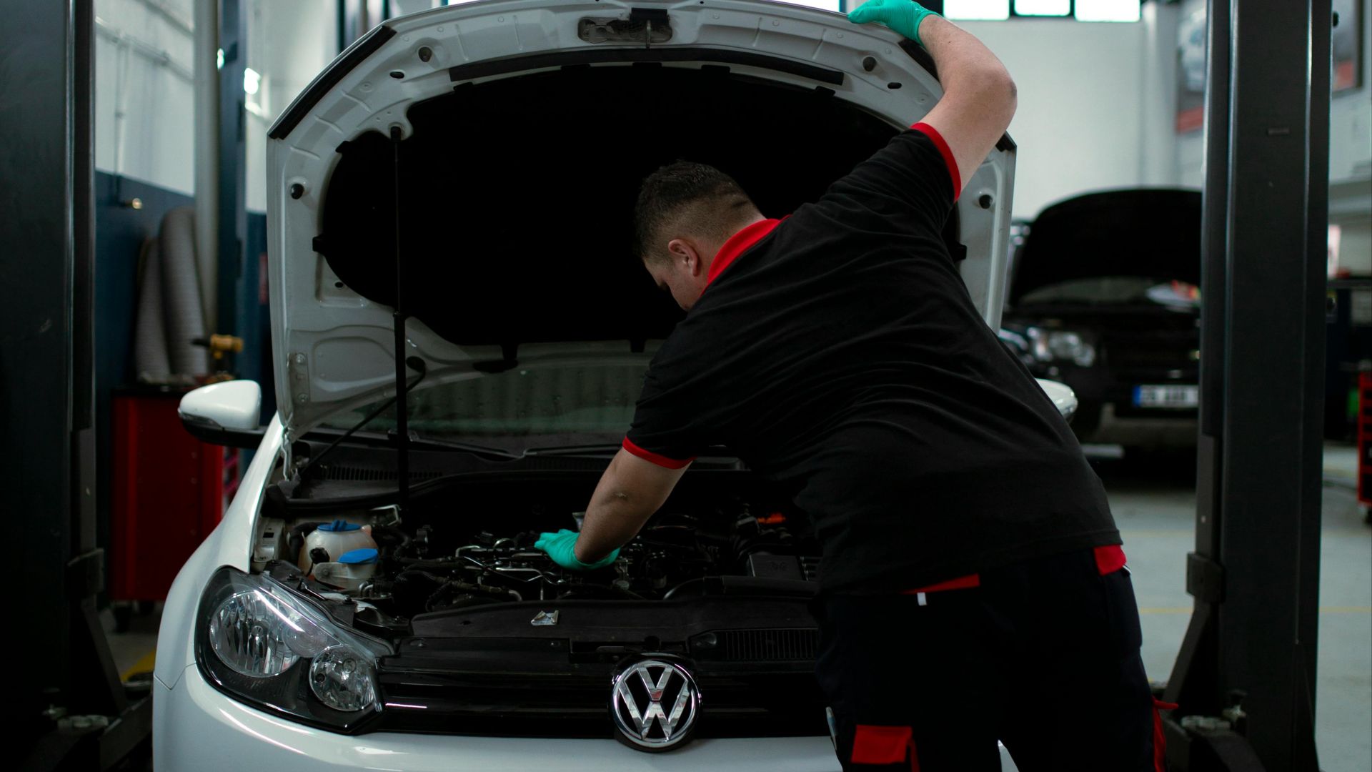 A mechanic works on a Volkswagen engine in an indoor garage setting, showcasing automotive repair skills.