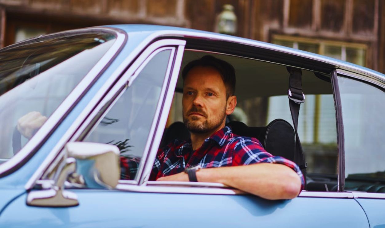 Thoughtful man driving car near old city house
