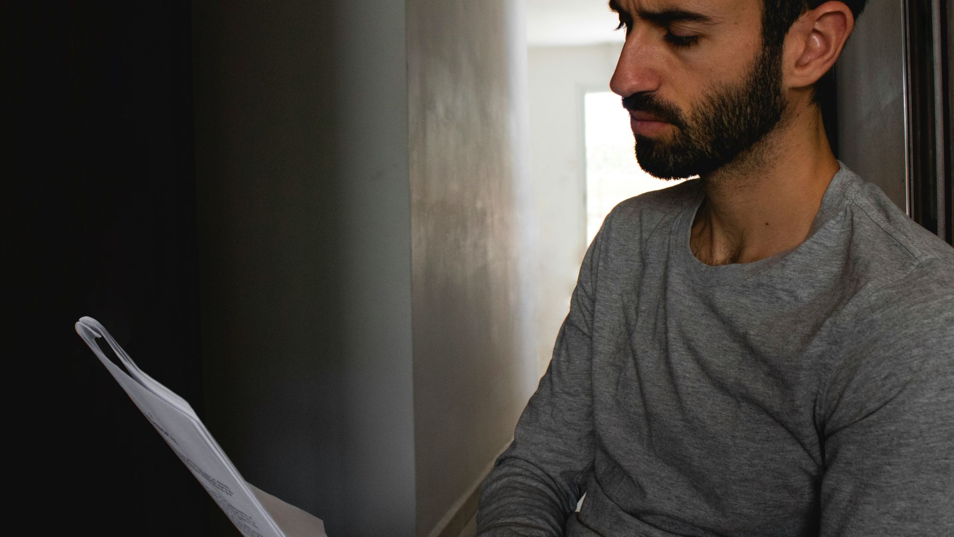 man in gray crew neck shirt holding white printer paper