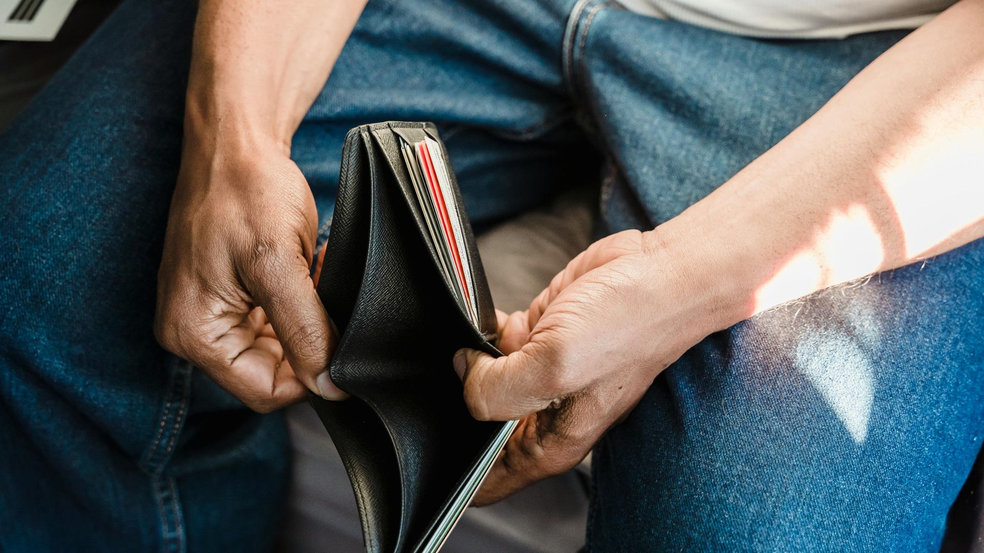 Close-up of a man holding an empty wallet, symbolizing financial crisis and hardship.