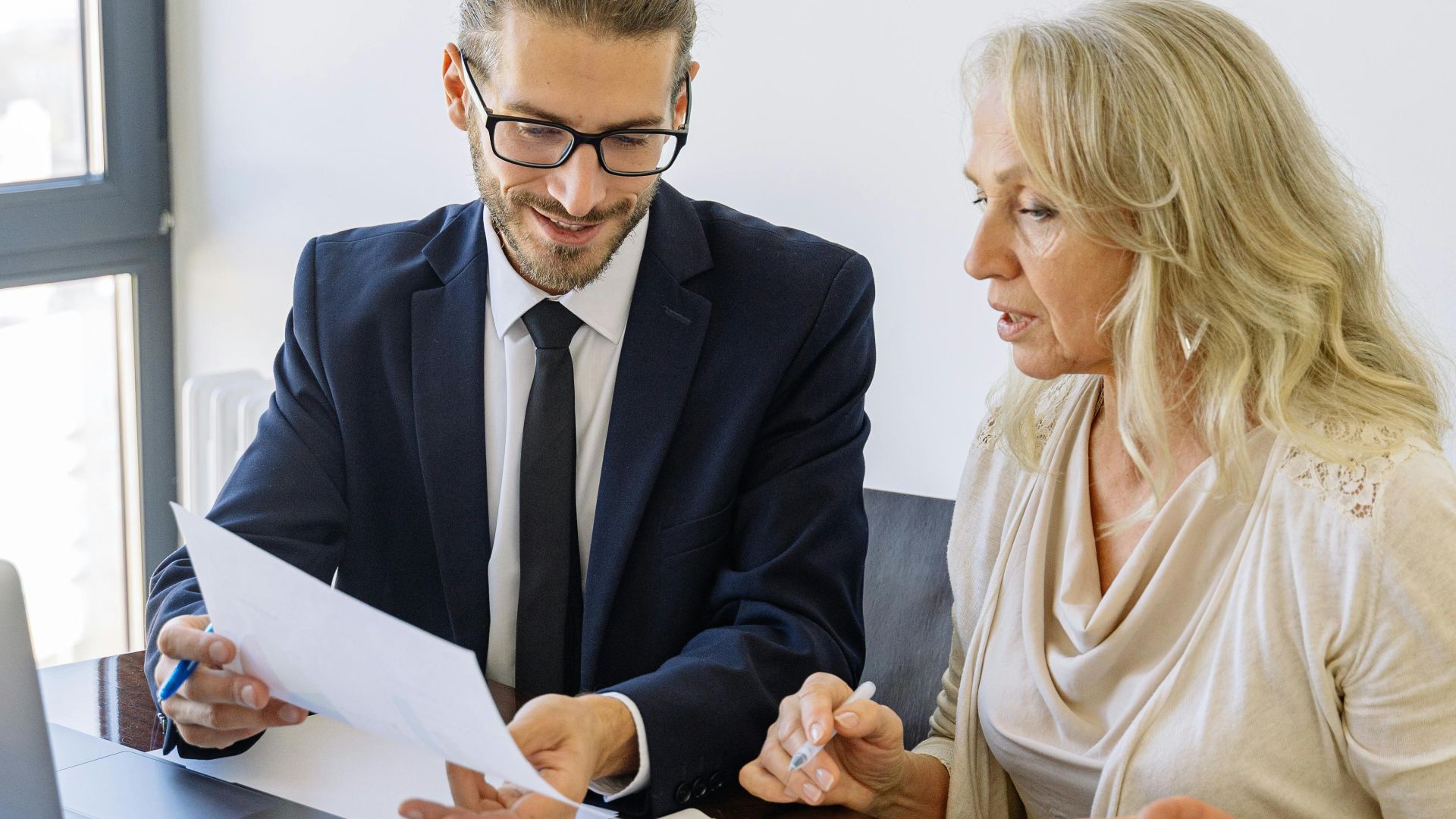 Two business professionals reviewing financial documents and graphs during a meeting.