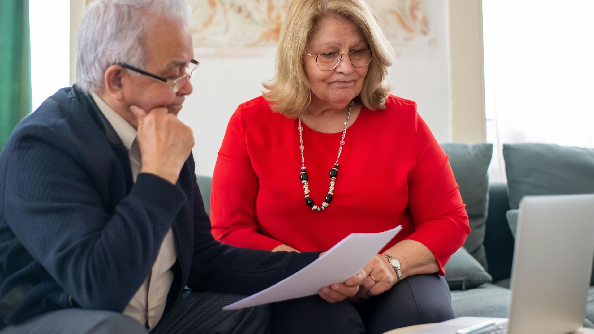 Elderly couple reviewing financial documents together at home in Portugal.