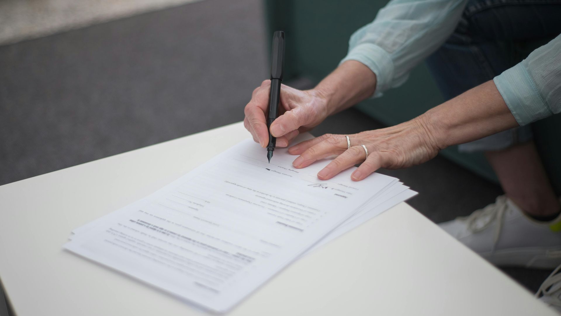 A person signing important legal documents on a table, emphasizing business and professionalism.