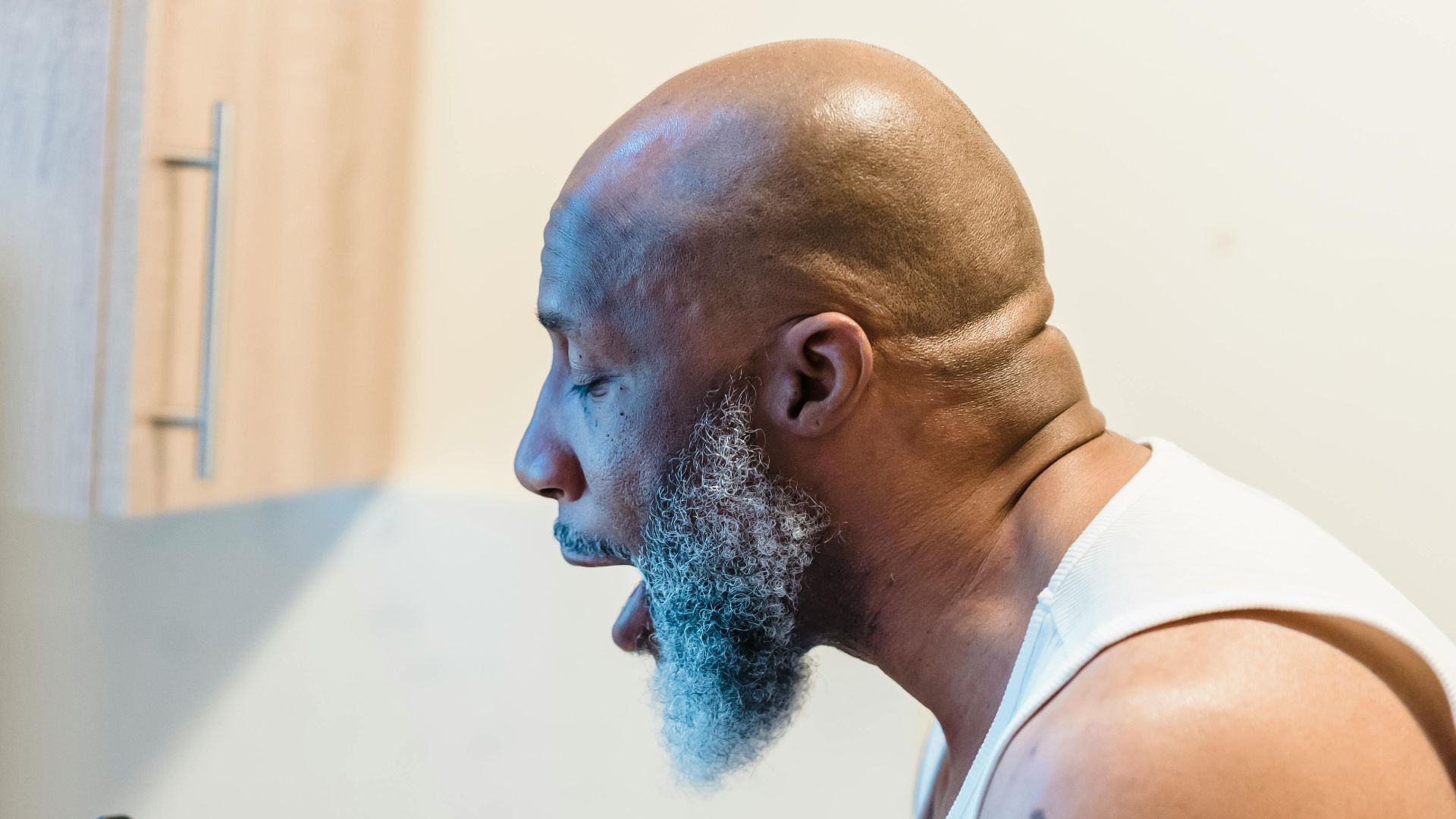 An adult man angrily shouting at a smartphone in his kitchen, expressing frustration.