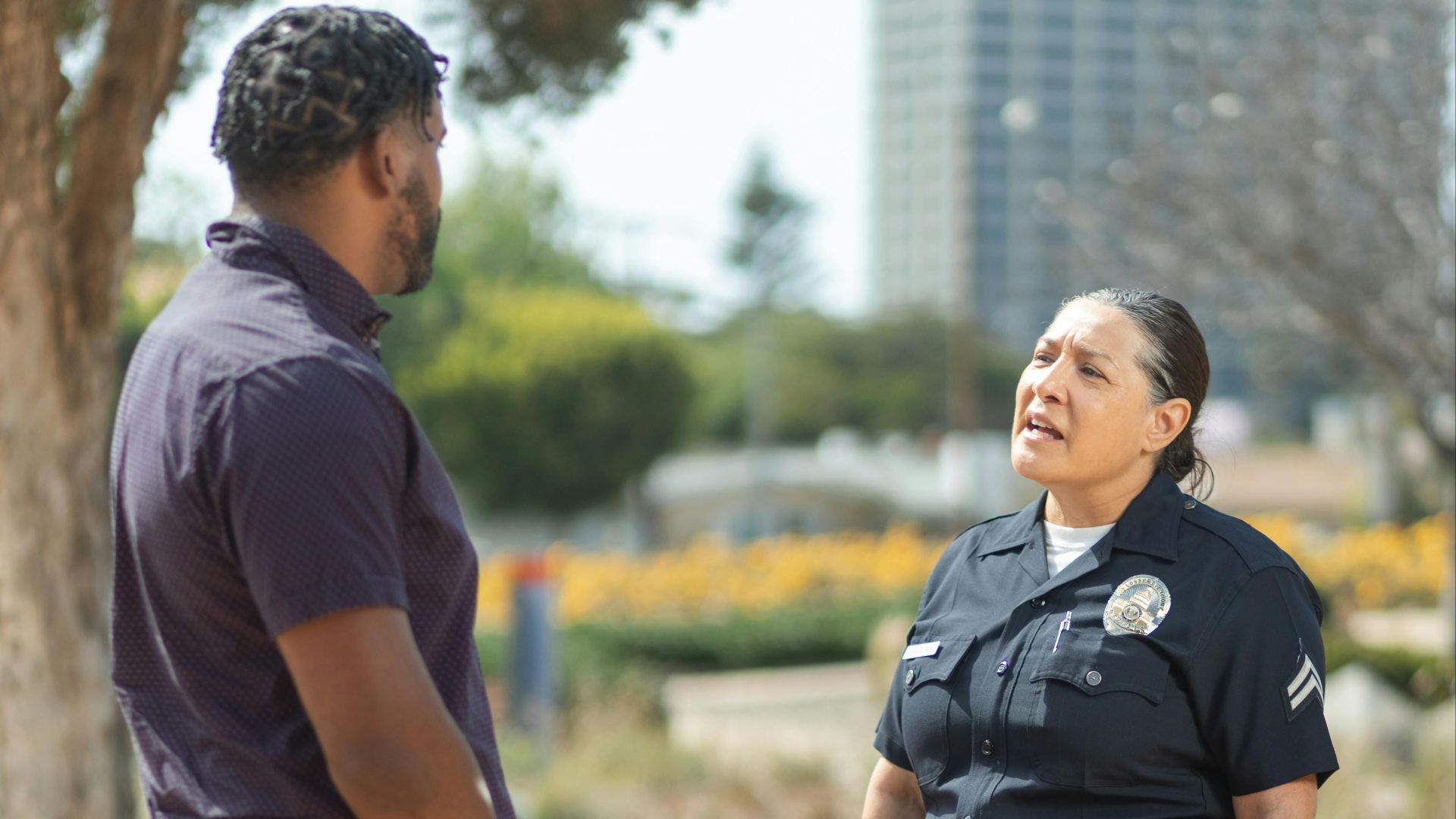 A police officer in uniform converses with a man on a sunny day, showcasing community engagement.