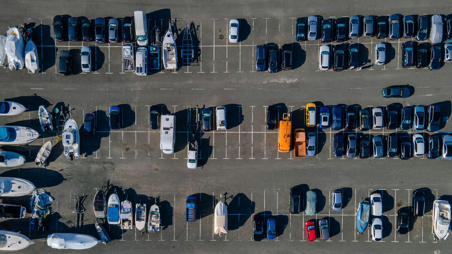 Aerial view showcasing parked boats and cars in a sunny lot. Ideal for transport themes.