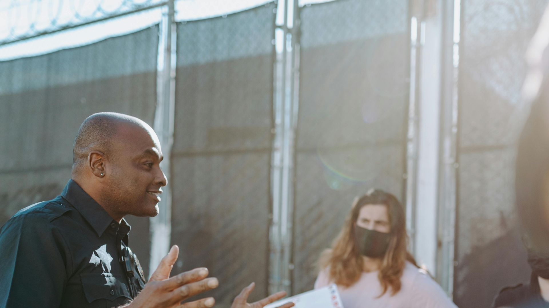 A police officer converses with protesters holding signs outdoors, demonstrating active communication.