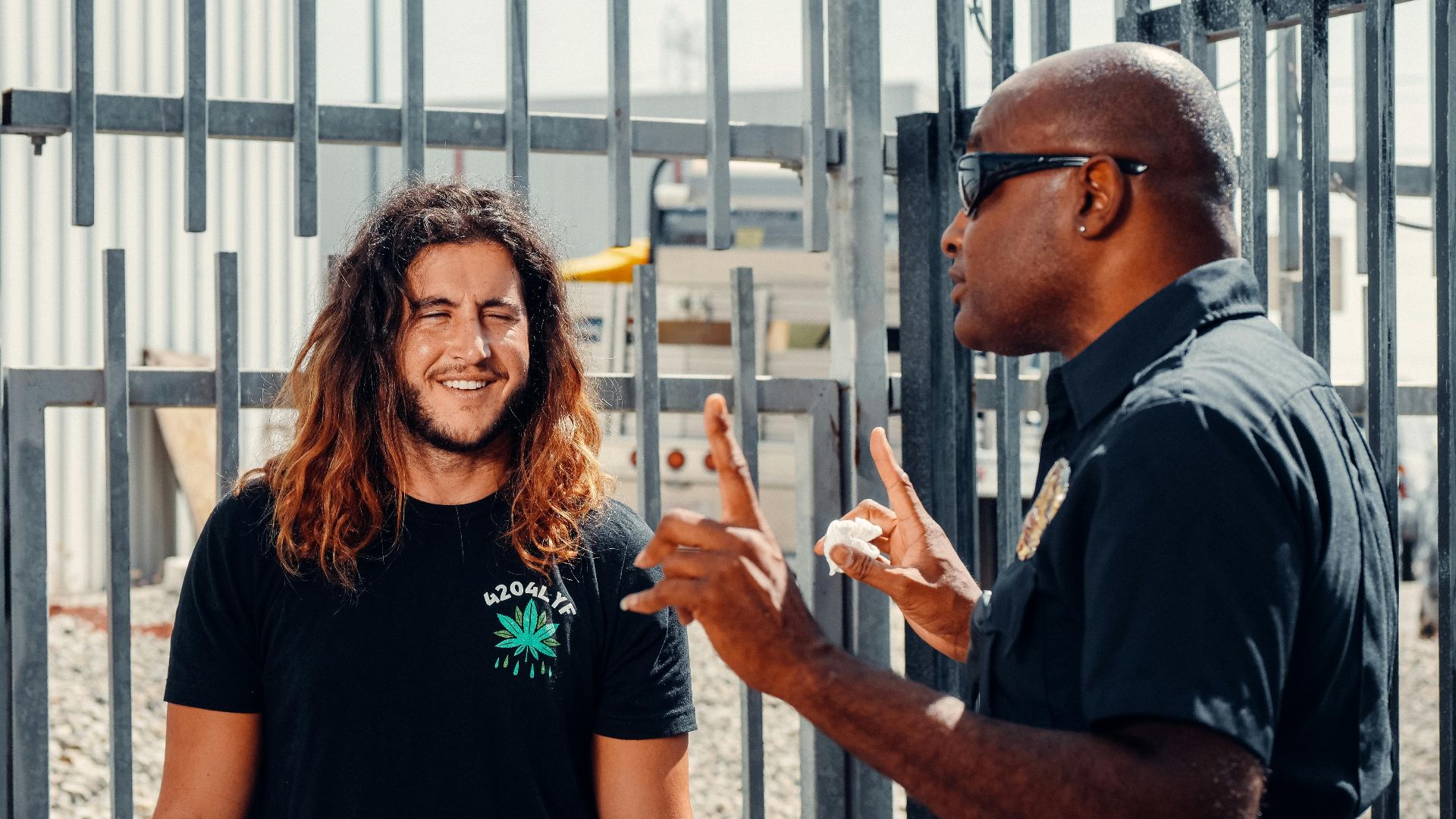 A police officer engages in conversation with a civilian outside on a sunny day.