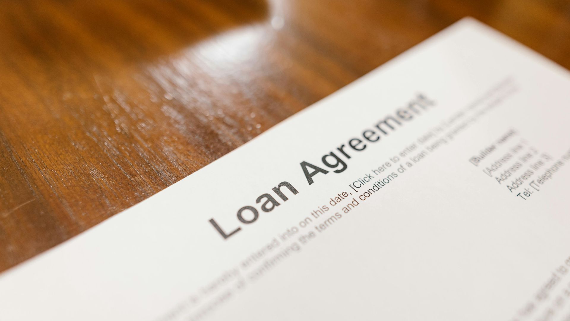 Detailed loan agreement document close-up on a wooden table representing legal and financial concepts.