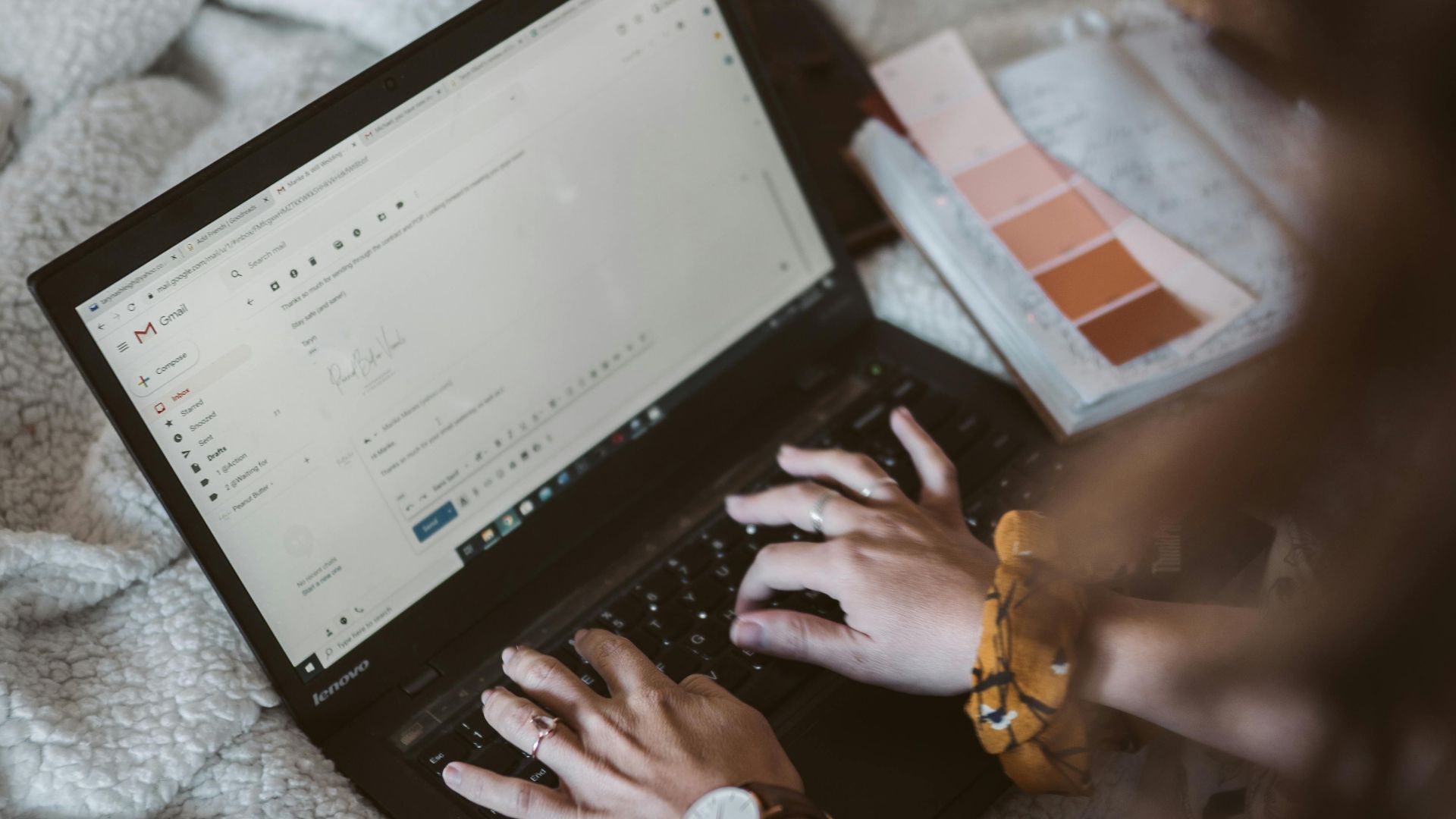 Adult woman typing on a laptop in a cozy home setting, emphasizing remote work and comfort.