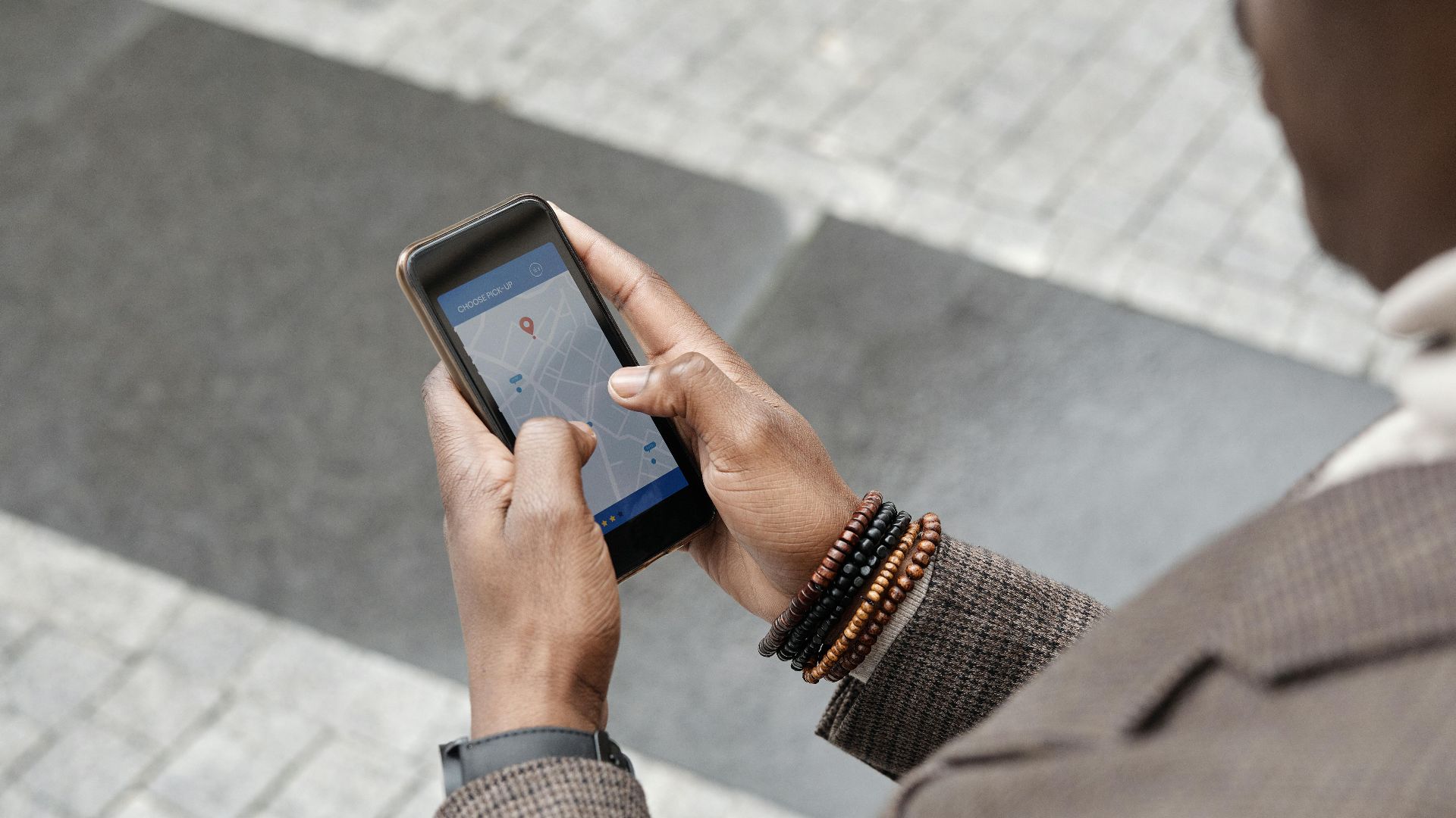 A stylish professional adult using a smartphone with a navigation app on an urban street.