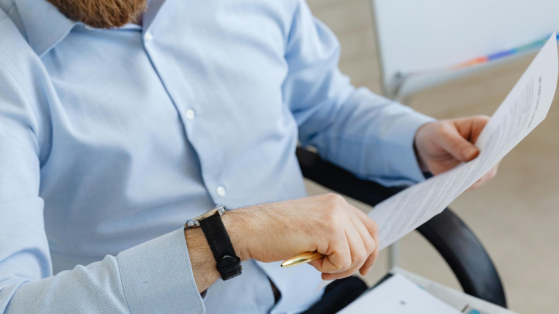 Businessman reviewing papers in office setting, highlighting analysis and attention to detail.