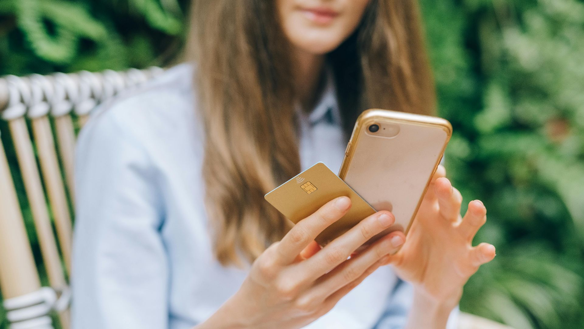 A woman making an online purchase using a smartphone and credit card outdoors.