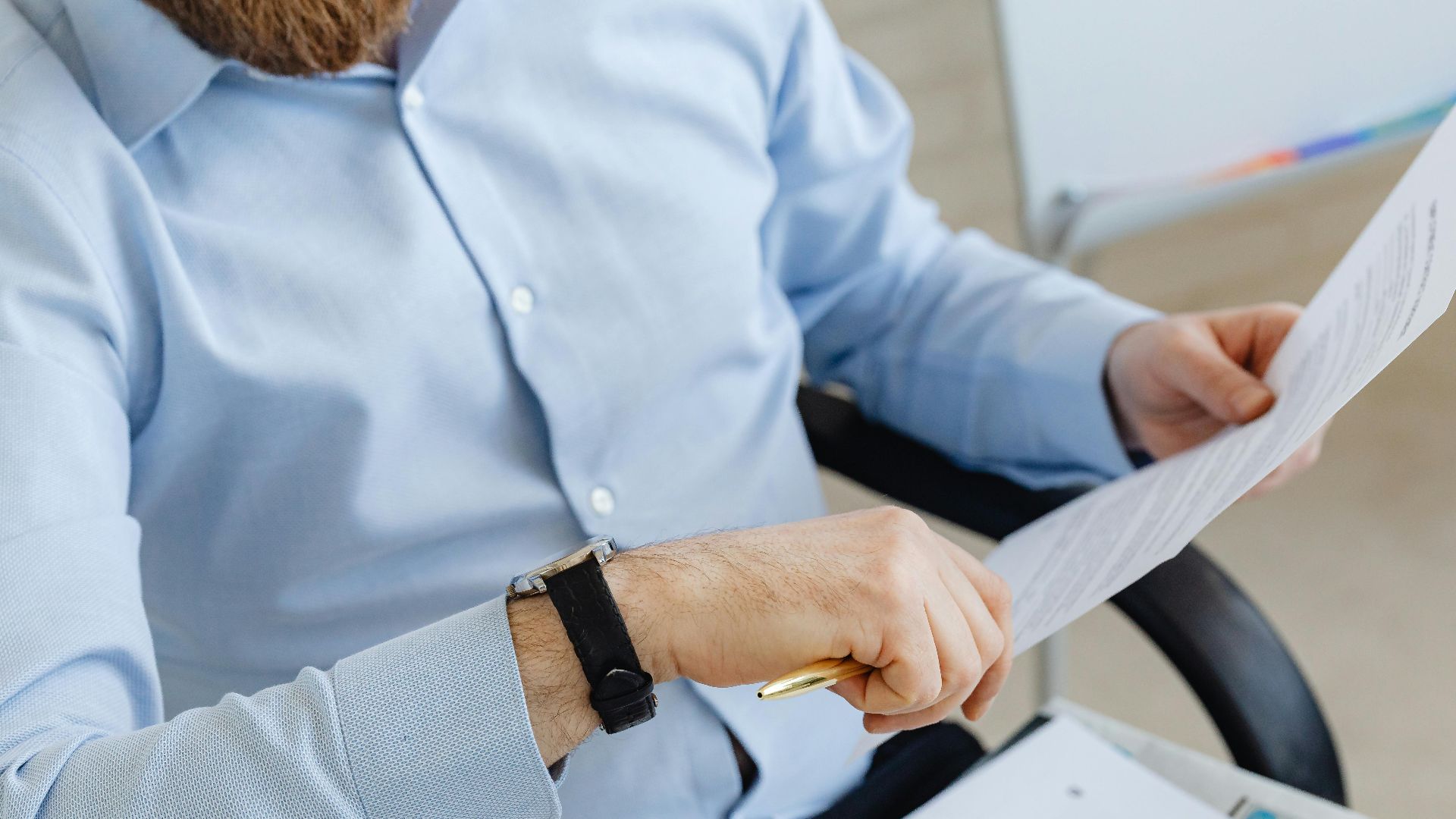 Businessman reviewing papers in office setting, highlighting analysis and attention to detail.