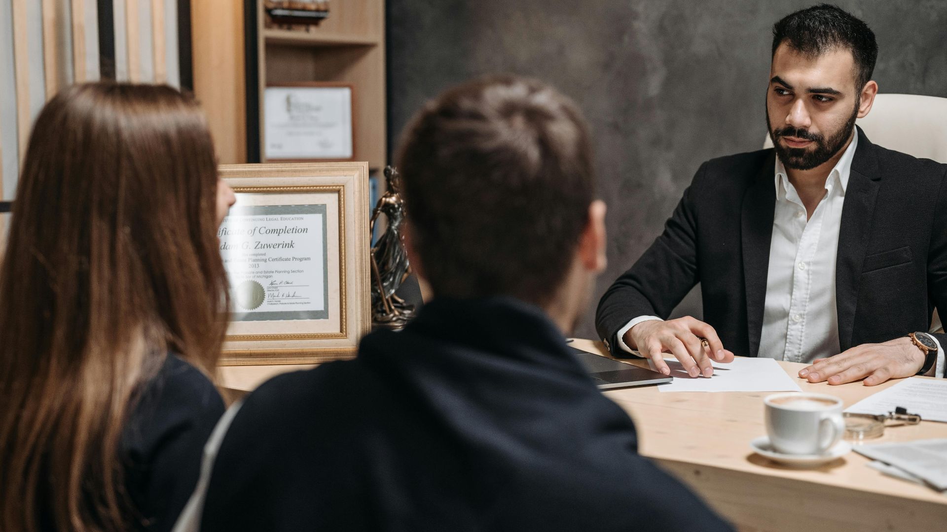 A lawyer in an elegant office meeting with clients, discussing documents.