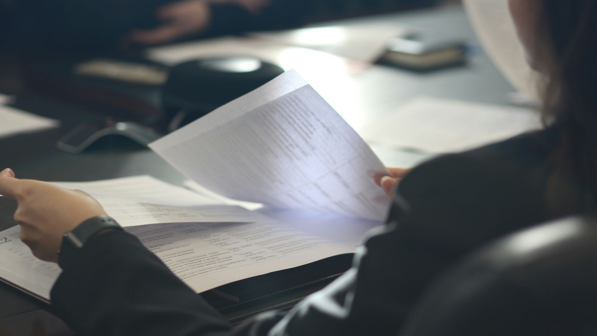 a woman sitting at a table reading a paper