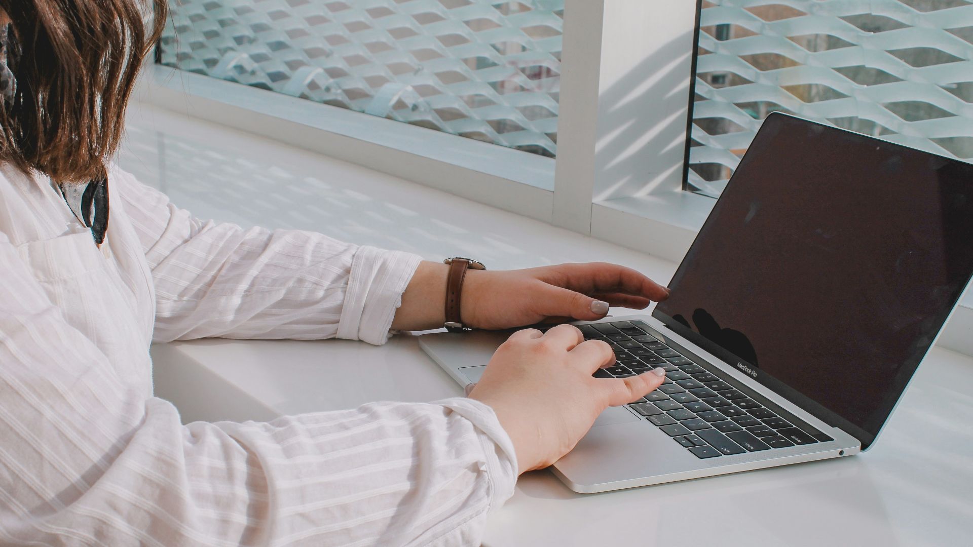person in white long sleeve shirt using macbook pro