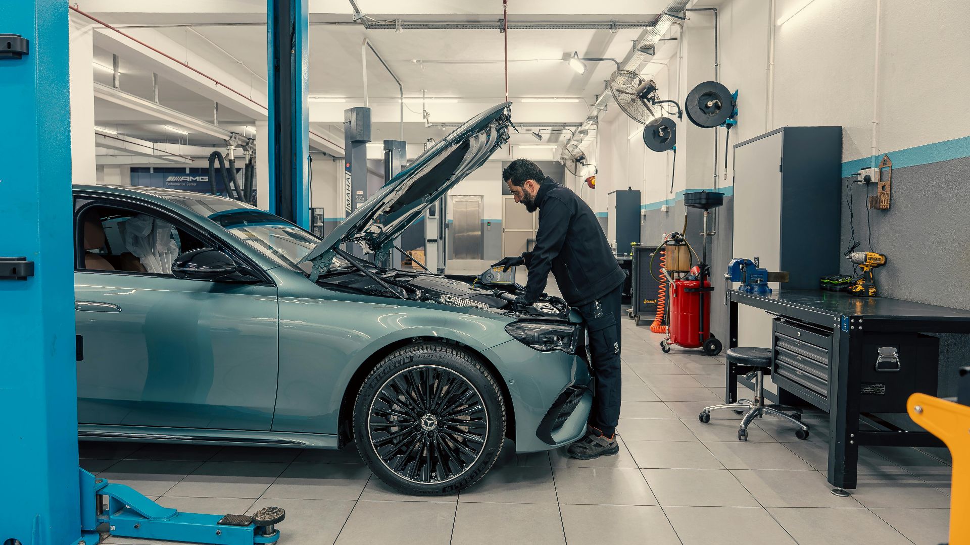 Mechanic inspecting a luxury car inside a well-equipped garage. Vehicle maintenance setting.