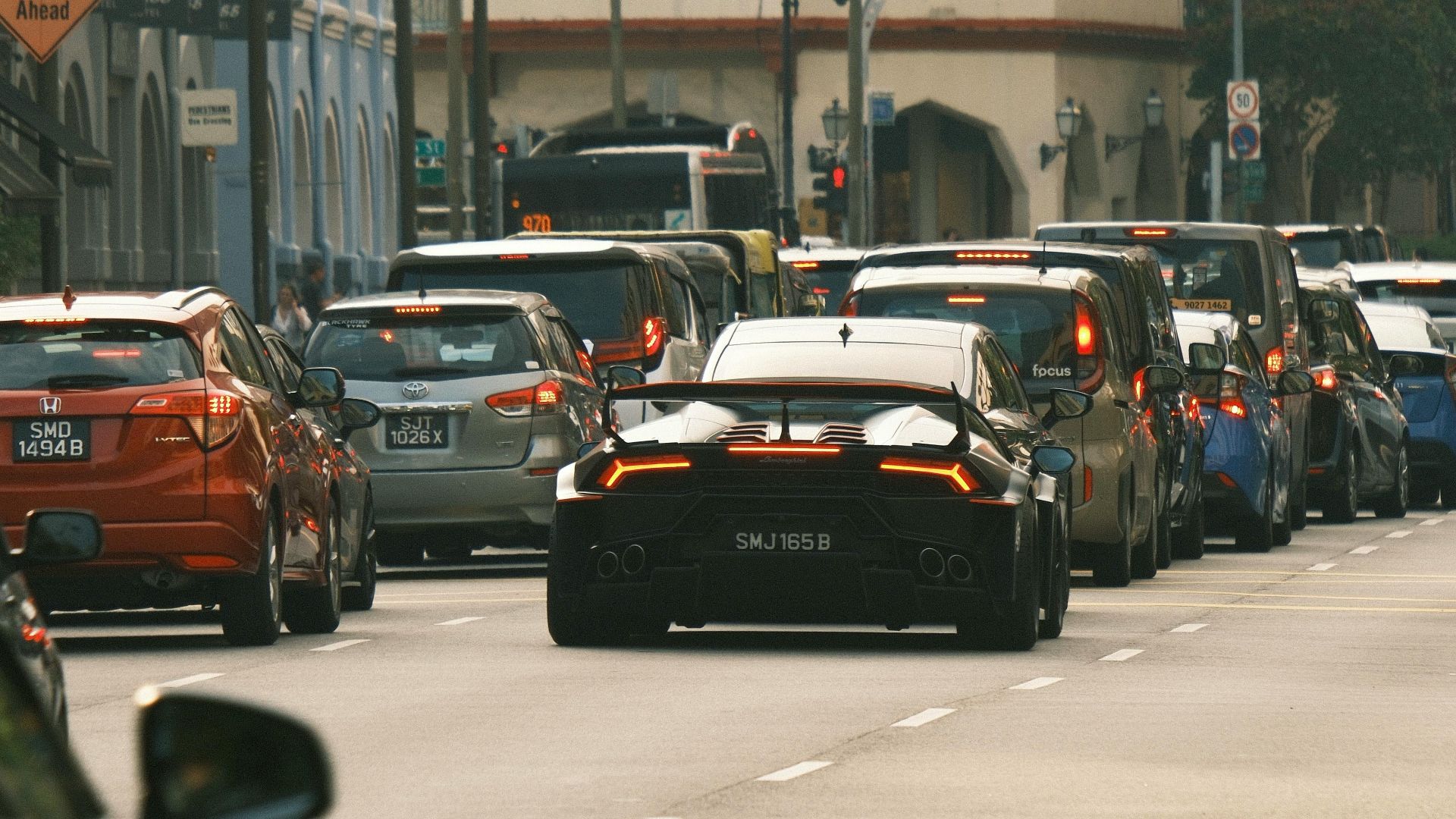 A sleek sports car amidst city traffic during the day, showcasing urban life.