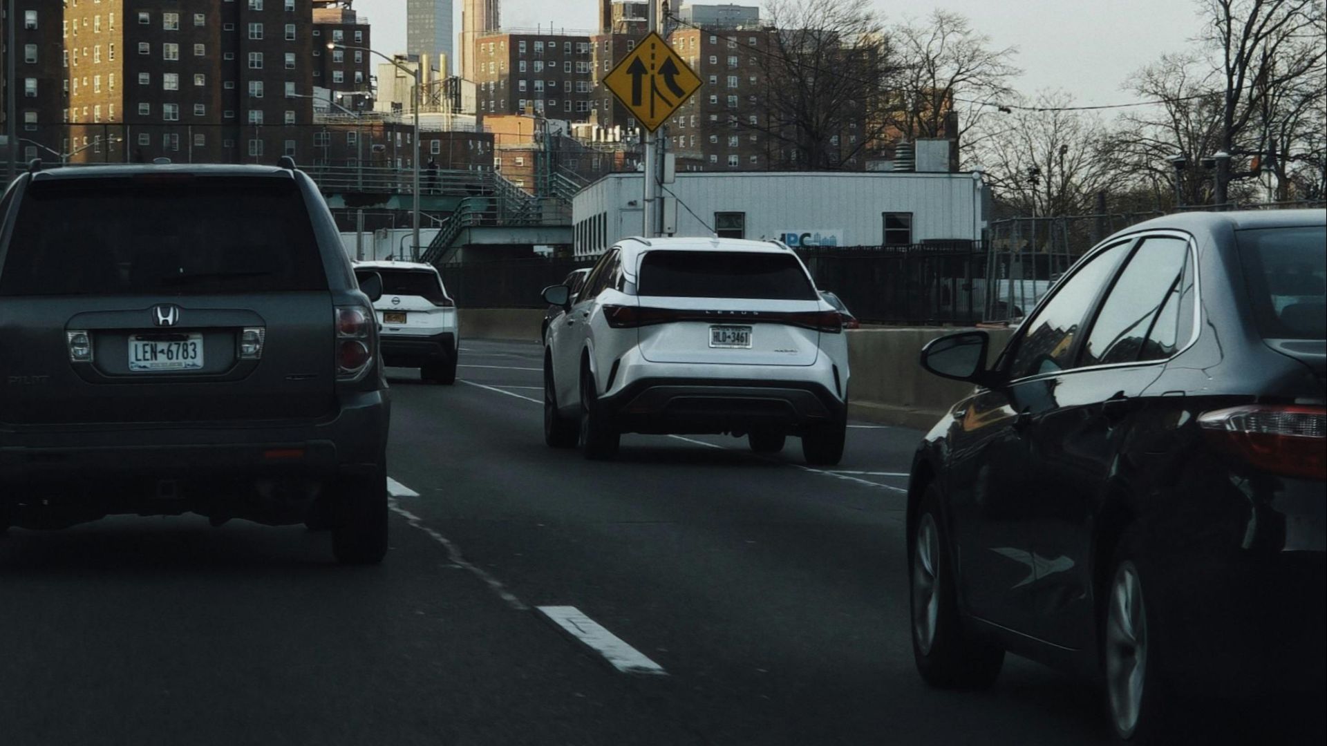 Vehicles on a city highway with industrial chimneys in the background.
