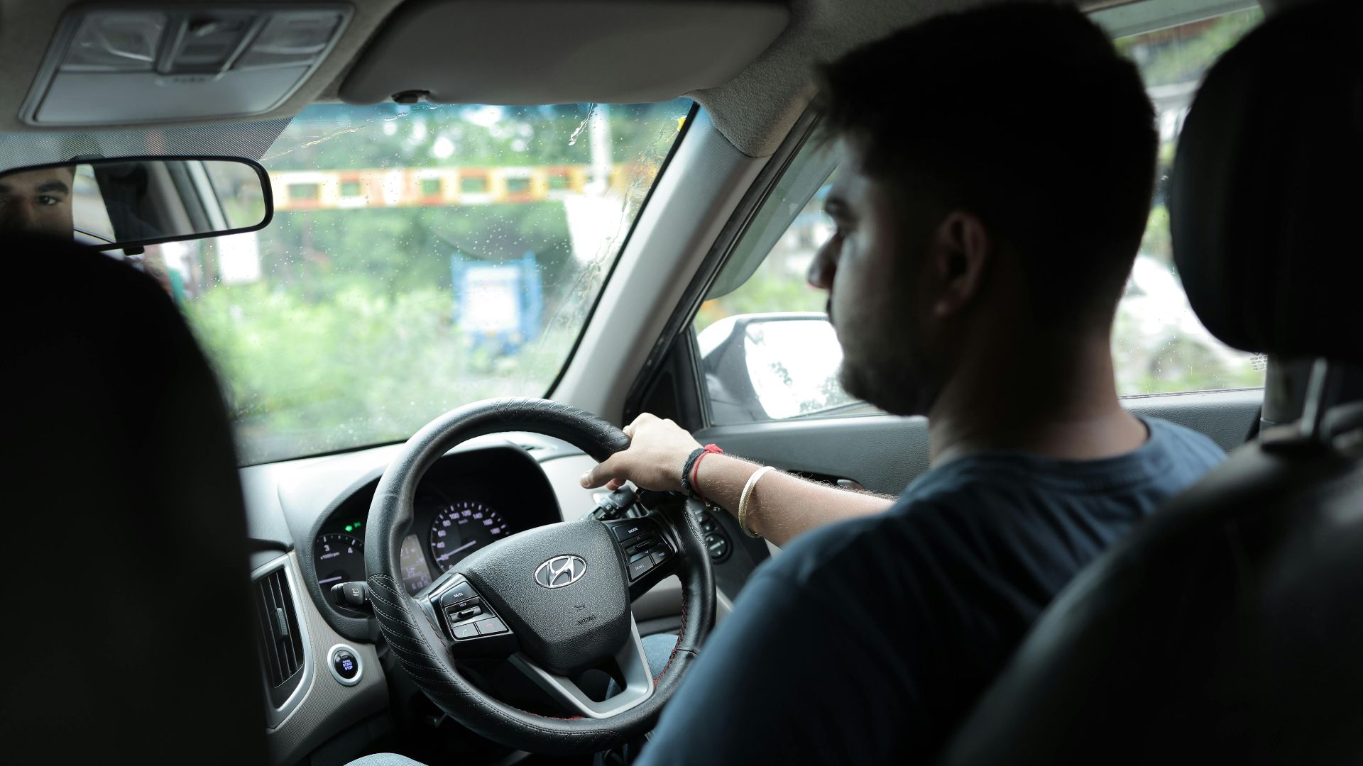 A young man is driving a car attentively, captured from the backseat for an authentic candid moment.
