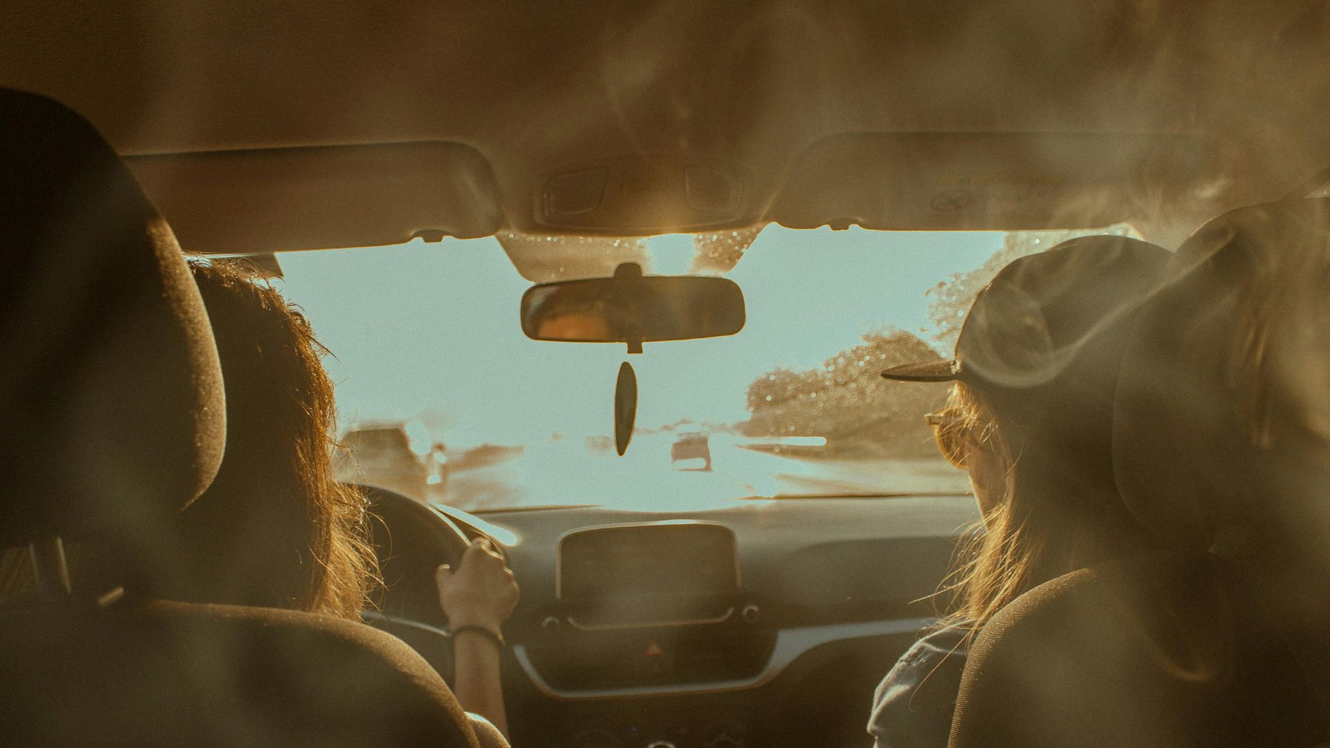 Two women driving on a sunny day showcasing road trip adventure in summer.