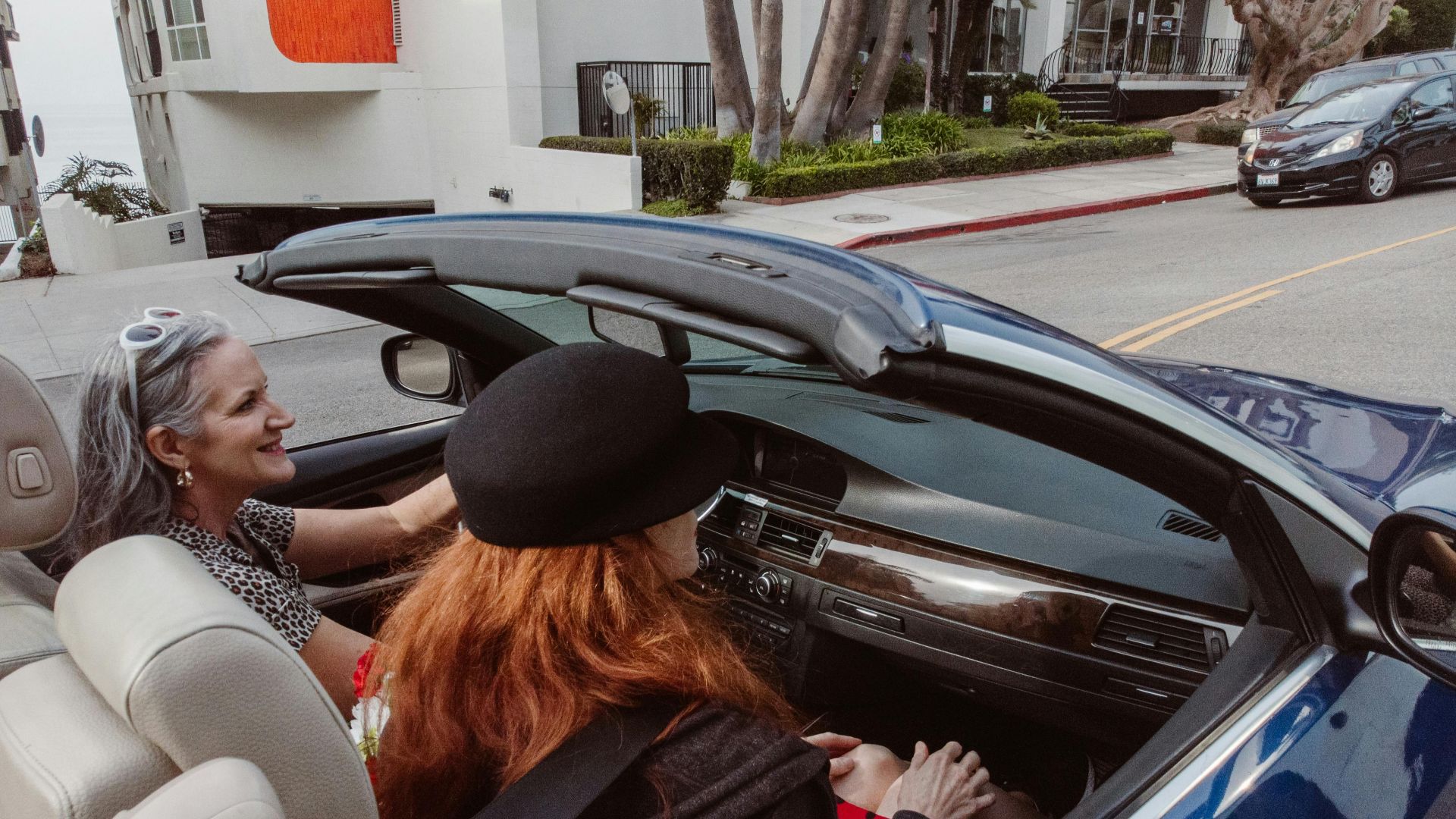 Two women enjoy a leisurely drive in a convertible at Redondo Beach, capturing the essence of freedom and adventure.